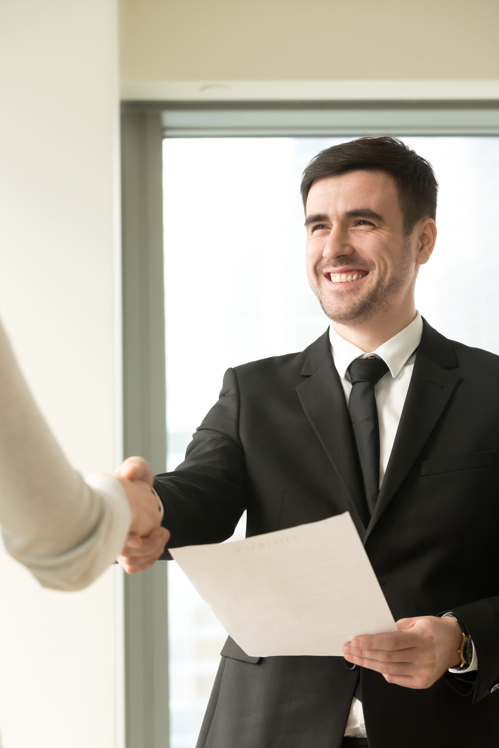 Happy smiling businessman wearing suit shaking female hand, hold